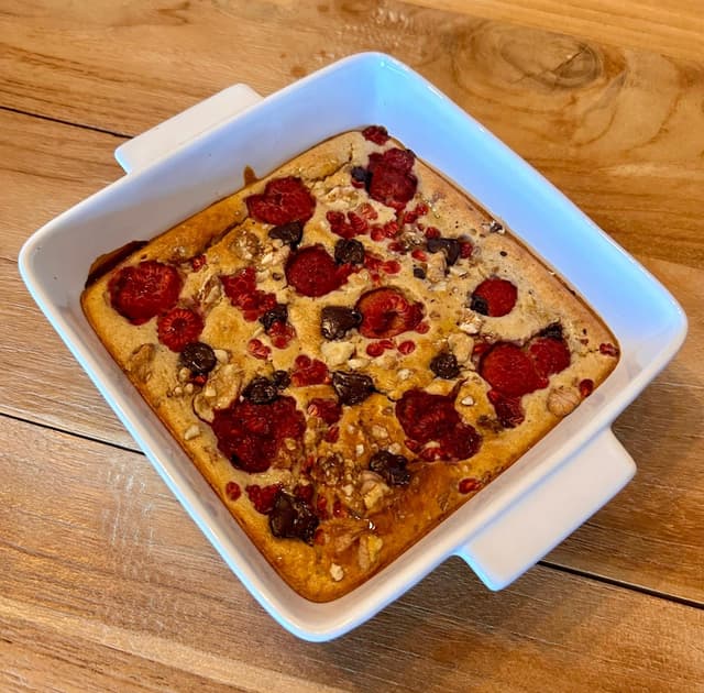 Healthy baked oats pie with banana, oat milk, raspberries, and dark chocolate. A delicious and nutritious breakfast or dessert option!